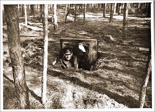 A Dutch policeman looks out the hatch of a small bunker that served as a hiding place for Dutch Jews in the Eibergen region in 1942-1943